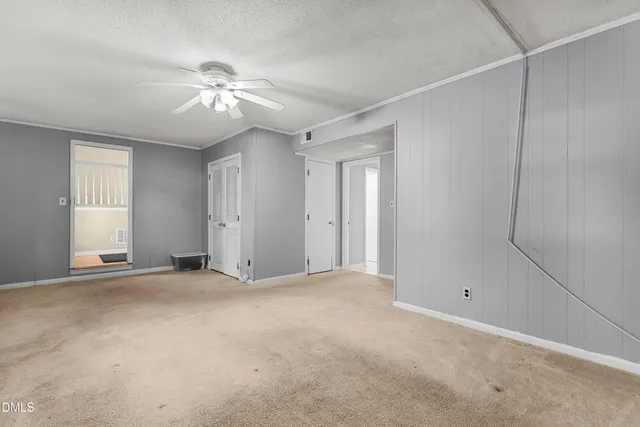 a view of an empty room with a ceiling fan and window