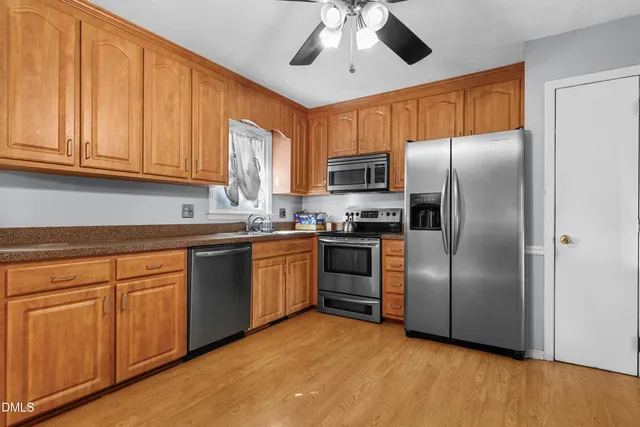 a kitchen with stainless steel appliances granite countertop a refrigerator a sink dishwasher a stove with wooden cabinets and floor