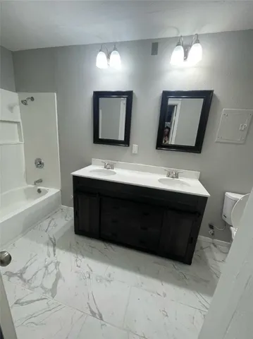 a bathroom with a double vanity sink mirror and bathtub