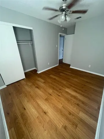 an empty room with wooden floor closet and windows