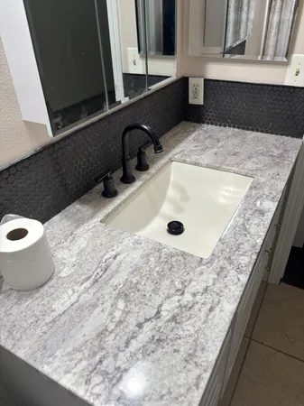 a bathroom with a granite countertop toilet sink and mirror