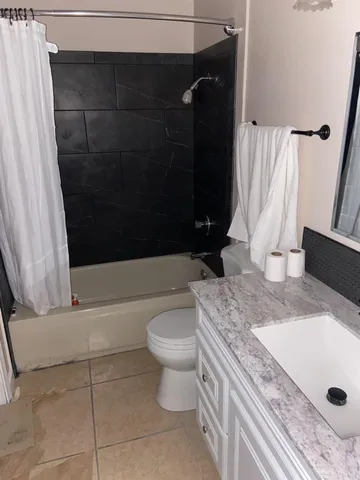 a bathroom with a granite countertop sink a toilet and bathtub