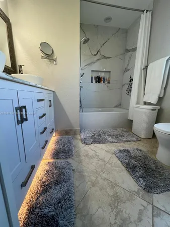 a bathroom with a granite countertop sink a toilet and shower