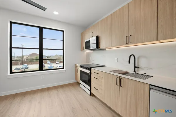 a kitchen with stainless steel appliances a sink cabinets and a window