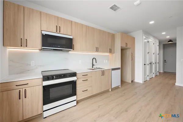 a kitchen with cabinets stainless steel appliances and wooden floor