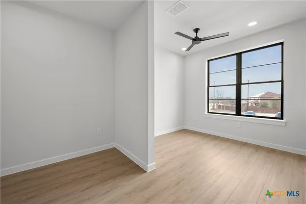 an empty room with wooden floor and windows