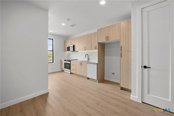 a view of a kitchen with wooden floor and electronic appliances