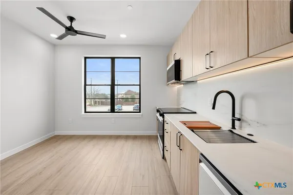 a view of a kitchen with a sink and dishwasher with wooden floor
