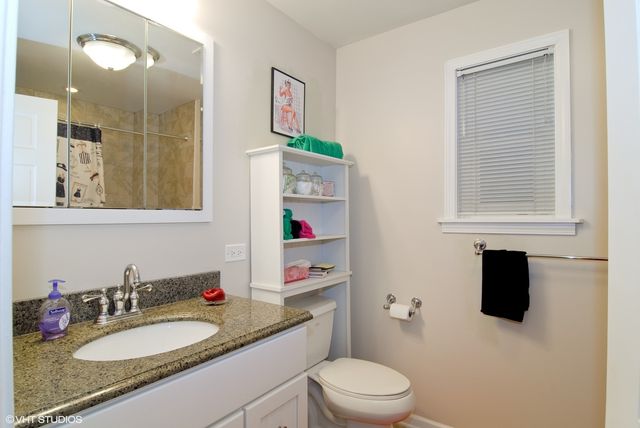 a bathroom with a granite countertop sink toilet and a mirror