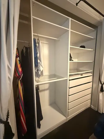 a view of walk in closet with clothes and shoes