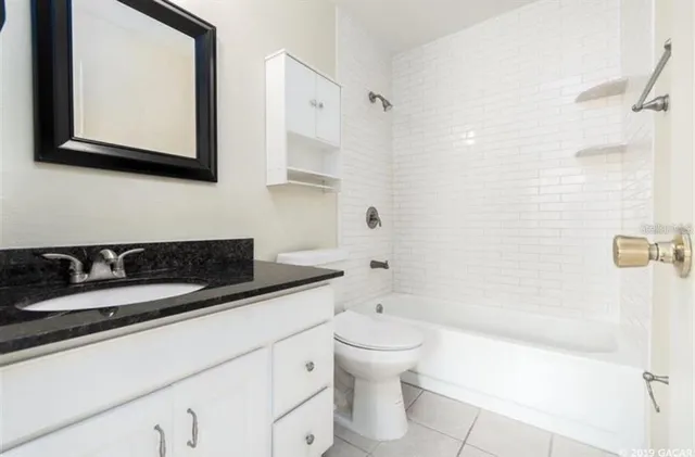 a bathroom with a granite countertop sink mirror vanity and toilet