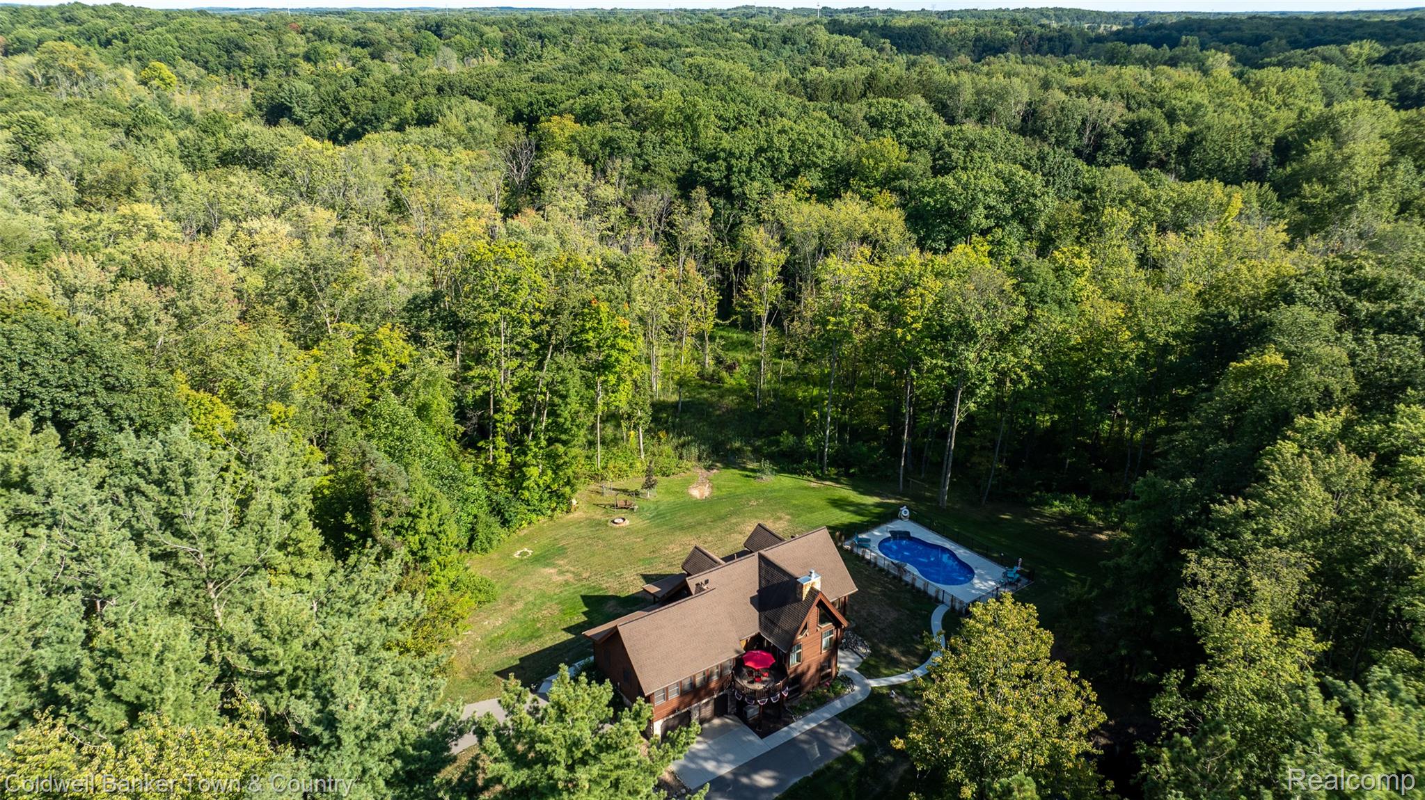 7023 Munsell Road Howell, MI 48843 - Photo 48 of 55 Expansive wooded grounds with a residential structure, a paved driveway, and an in-ground swimming pool