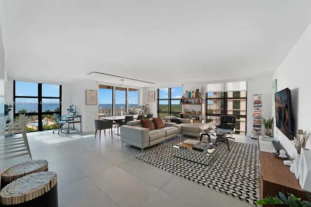 a living room with furniture a flat screen tv and a floor to ceiling window