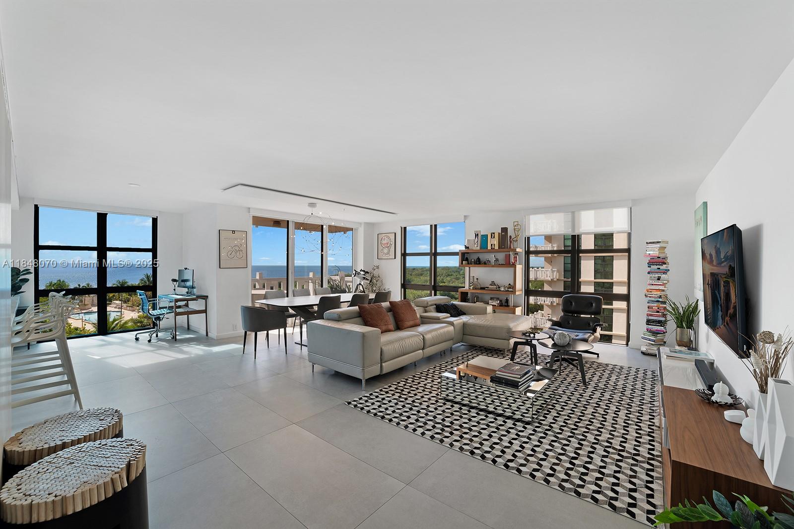 a living room with furniture a flat screen tv and a floor to ceiling window