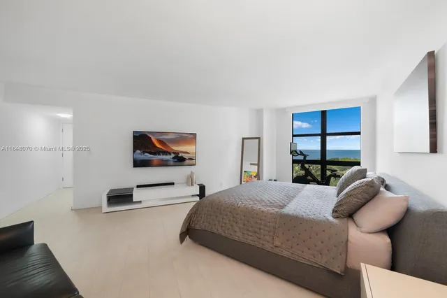 a bedroom with a bed a flat screen tv and window