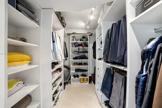 a view of walk in closet with clothes and shoes