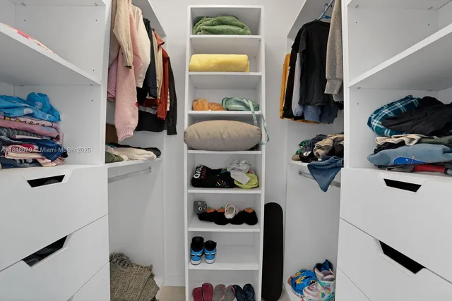 a view of walk in closet with clothes and shoes