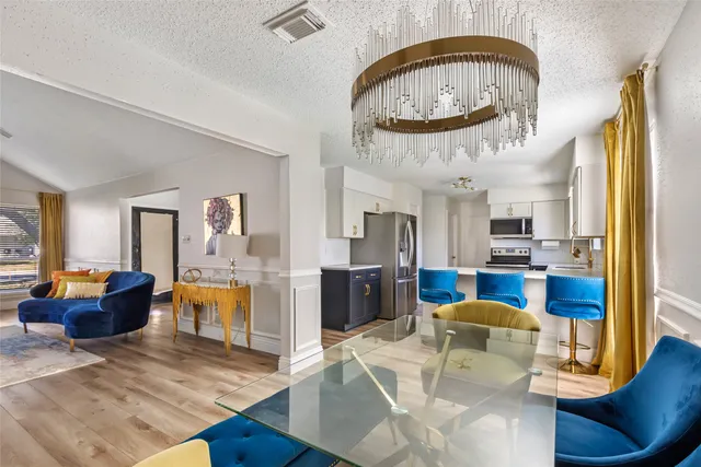 a living room with furniture a kitchen view and a chandelier