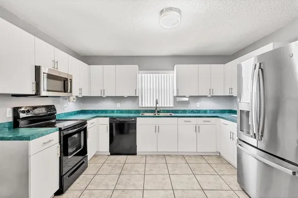 a kitchen with granite countertop a refrigerator sink and cabinets