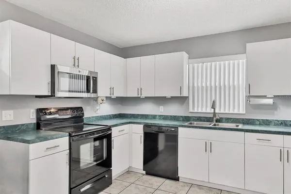 a kitchen with granite countertop white cabinets and stainless steel appliances