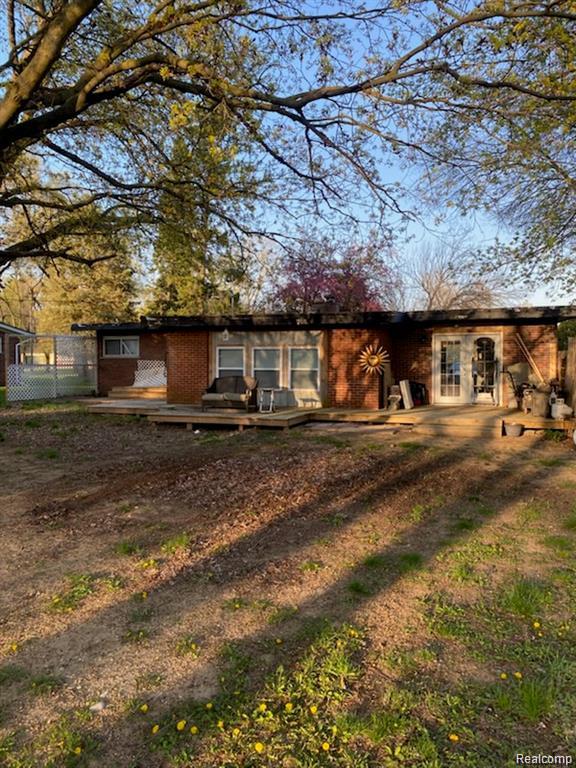 51575 Shelby Road Utica, MI 48316 - Photo 2 of 2 Brick exterior with a wooden deck, multiple windows, and a glass paneled door