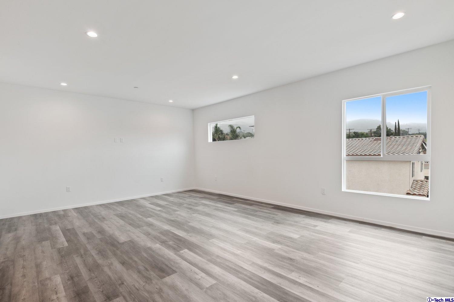 7064 Greeley Street, Unit 203 Tujunga, CA 91042 - Photo 20 of 42 an empty room with a fireplace and wooden floor