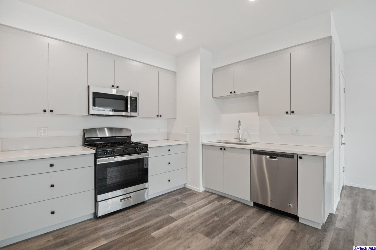 7064 Greeley Street, Unit 203 Tujunga, CA 91042 - Photo 21 of 42 a kitchen with stainless steel appliances a stove microwave and sink
