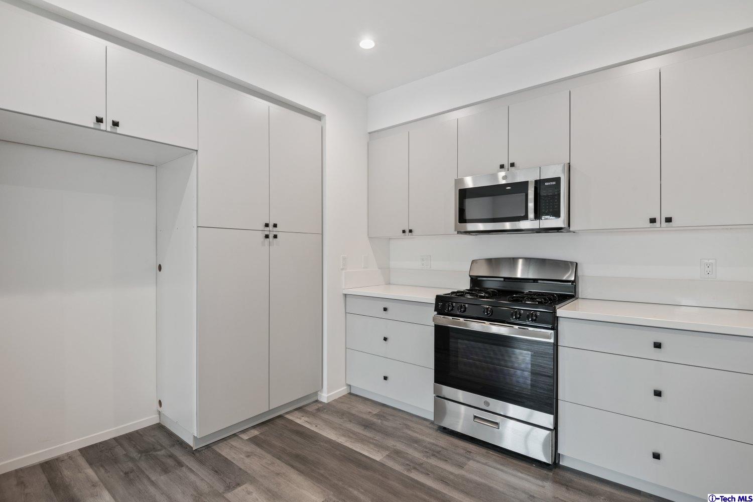 7064 Greeley Street, Unit 203 Tujunga, CA 91042 - Photo 24 of 42 a kitchen with white cabinets and stainless steel appliances