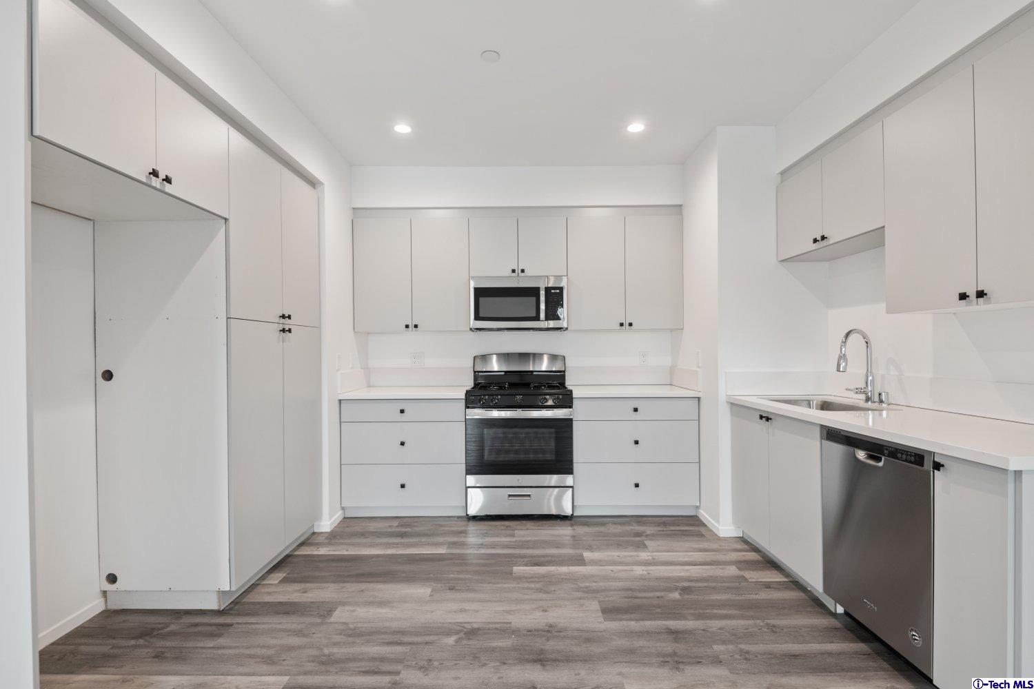 7064 Greeley Street, Unit 203 Tujunga, CA 91042 - Photo 25 of 42 a kitchen with white cabinets and stainless steel appliances