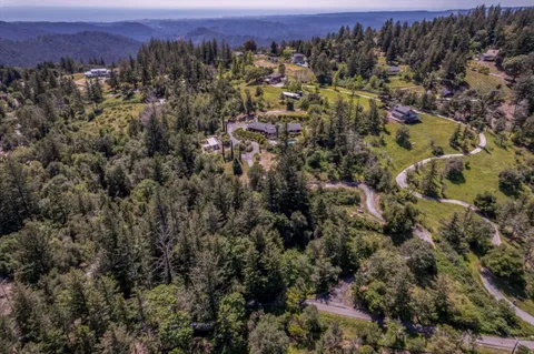 an aerial view of residential house with parking and trees