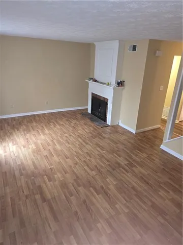a view of empty room with wooden floor and fireplace