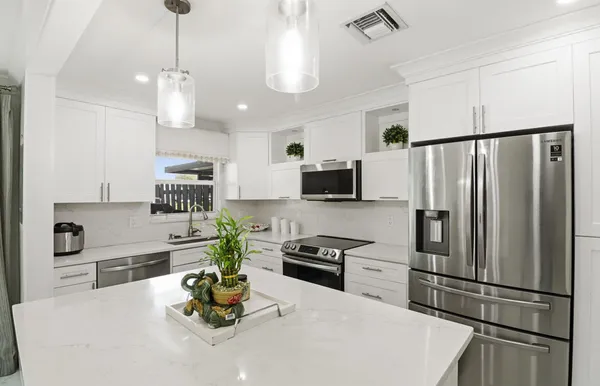 a kitchen with stainless steel appliances a refrigerator sink and white cabinets