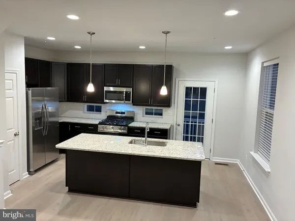 a large kitchen with a large counter top stainless steel appliances and cabinets