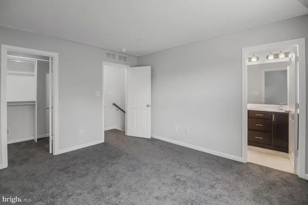 a view of an empty room with closet and bathroom