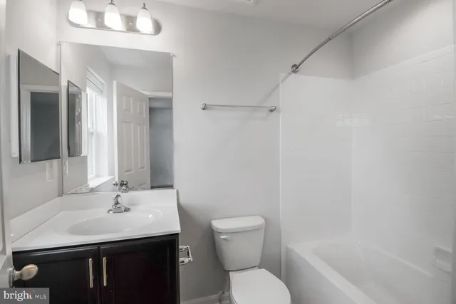 a bathroom with a granite countertop sink a toilet and shower
