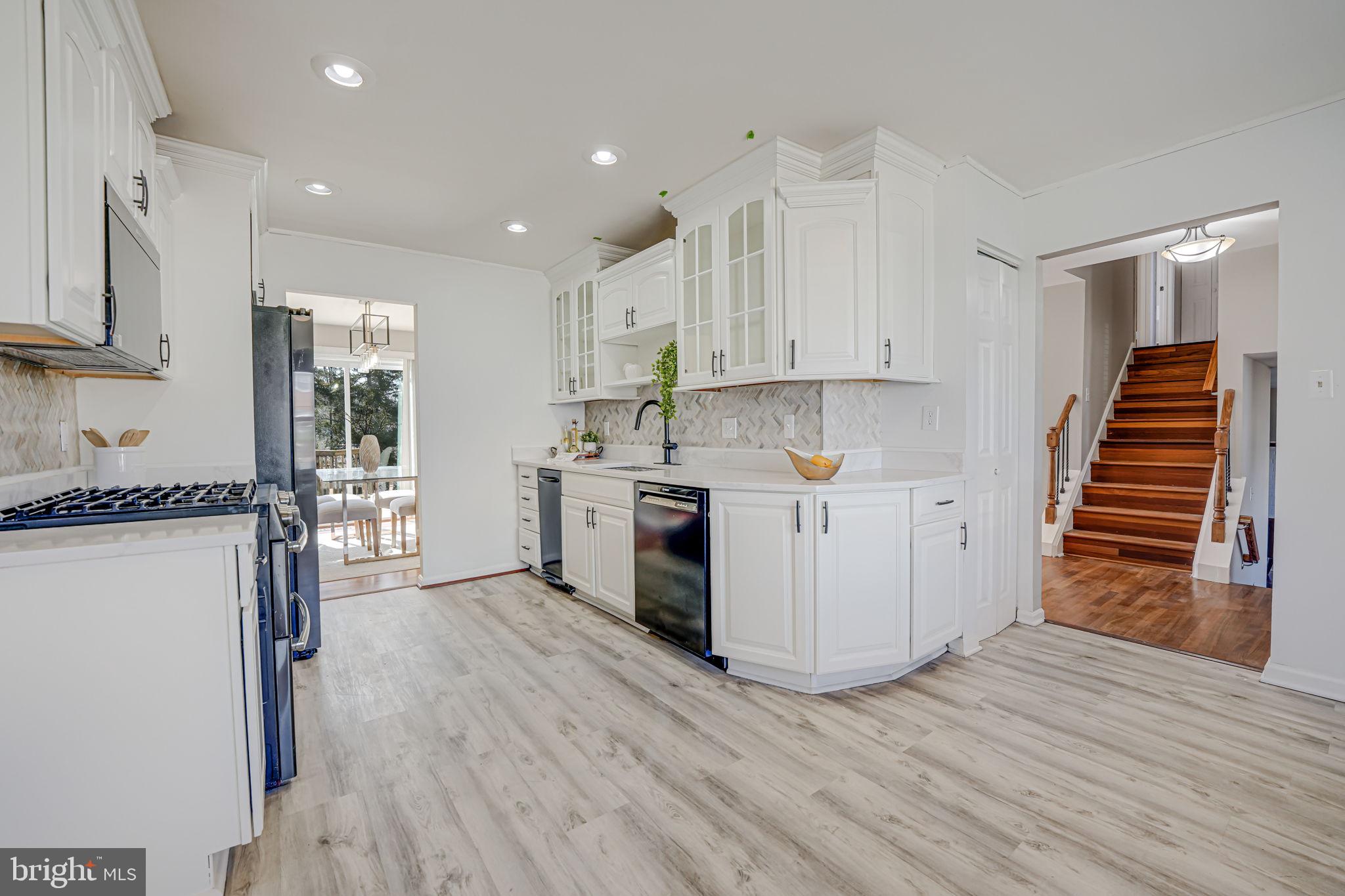 7829 Richfield Road Springfield, VA 22153 - Photo 13 of 34 a kitchen with wooden floors and white cabinets