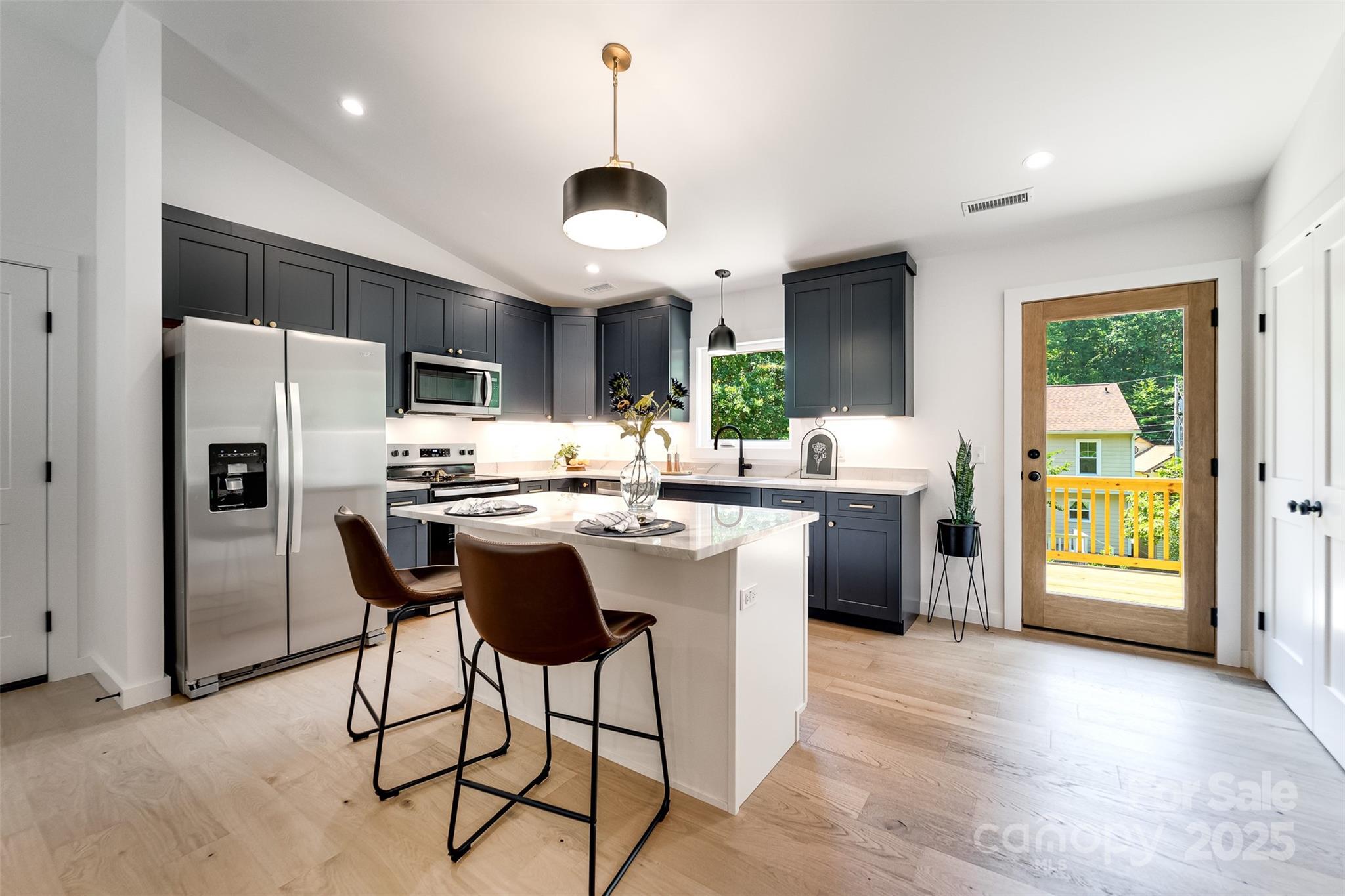 22 Crossing Lane Sylva, NC 28779 - Photo 13 of 44 a kitchen with stainless steel appliances a sink a stove a refrigerator cabinets and a dining table with wooden floor