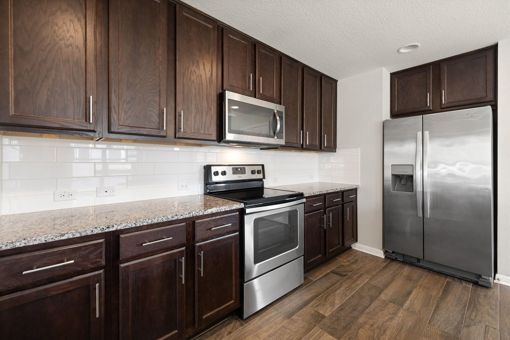 719 Coconut Grove Street Pflugerville, TX 78660 - Photo 16 of 31 a kitchen with granite countertop wooden cabinets stainless steel appliances and a sink