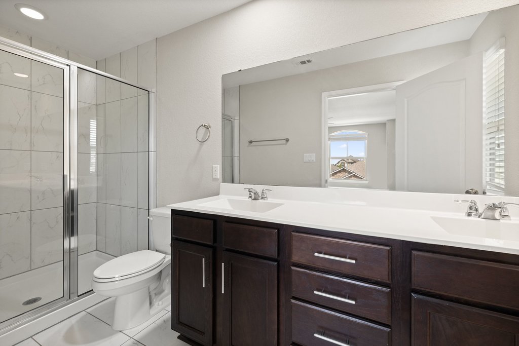 719 Coconut Grove Street Pflugerville, TX 78660 - Photo 19 of 31 a bathroom with a double vanity sink toilet and shower