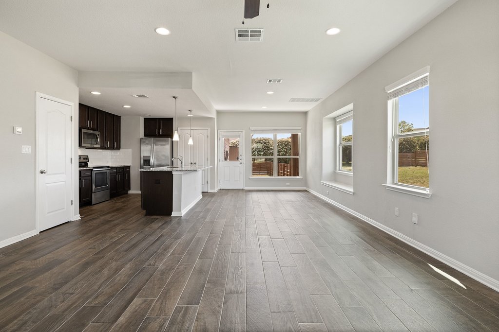 719 Coconut Grove Street Pflugerville, TX 78660 - Photo 5 of 31 an empty room with kitchen view and wooden floor