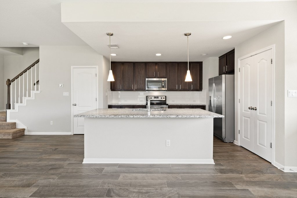 719 Coconut Grove Street Pflugerville, TX 78660 - Photo 10 of 31 a large kitchen with stainless steel appliances kitchen island a large counter top and wooden floors