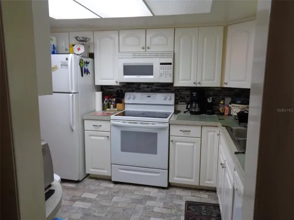 a kitchen with a refrigerator and white cabinets