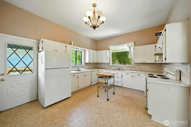 a kitchen with a refrigerator a sink dishwasher a stove and a dining table with wooden floor