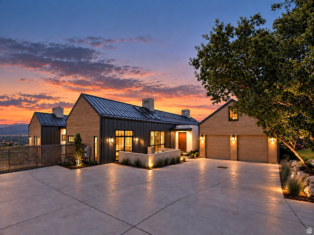 3939 Prospector Way Alpine, UT 84004 - Photo 1 of 43 Modern architectural design with a standing seam metal roof, extensive exterior lighting, a concrete driveway, and a two-car garage with wood-finish doors