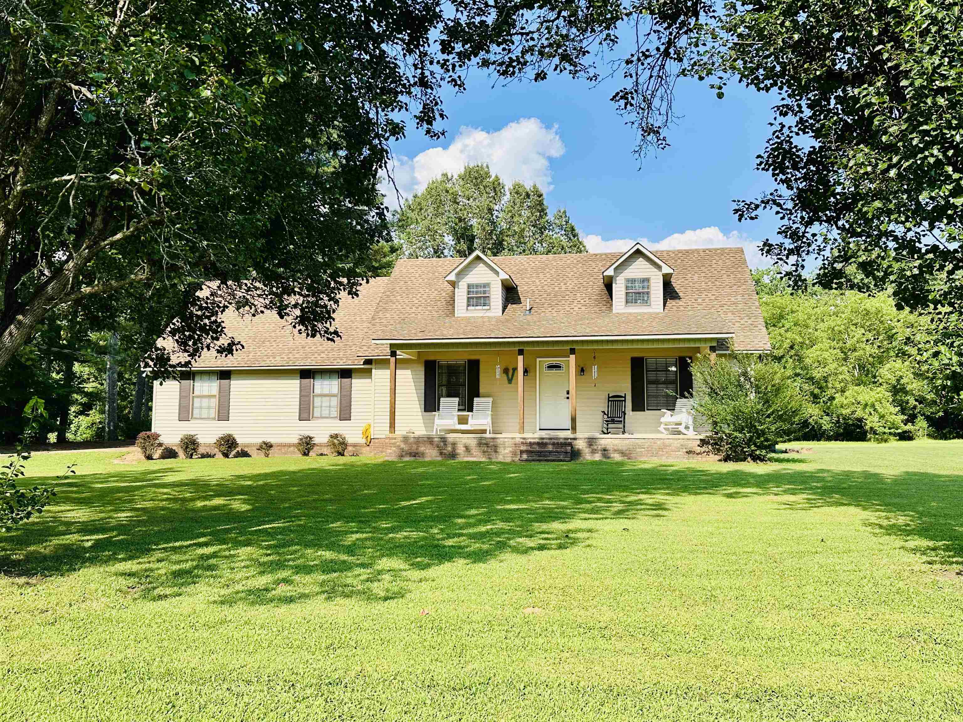 a view of a house with a big yard and large trees