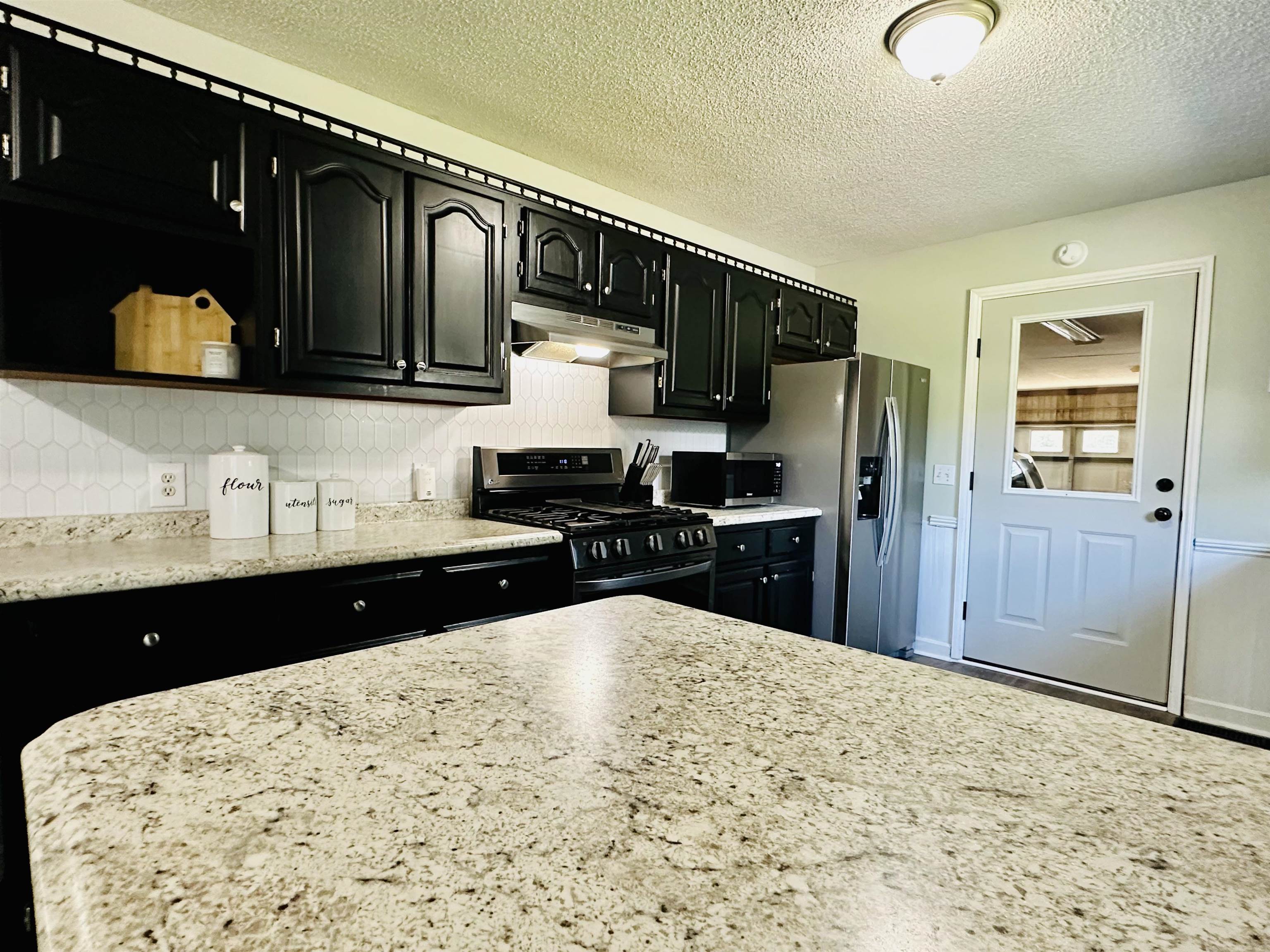 7120 Powell Chapel Road Hornsby, TN 38044 - Photo 6 of 29 a kitchen with stainless steel appliances kitchen island granite countertop a refrigerator and a sink
