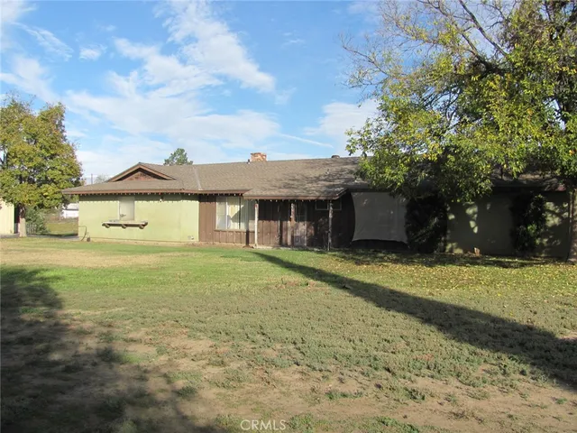 a view of a house with a yard and a large tree