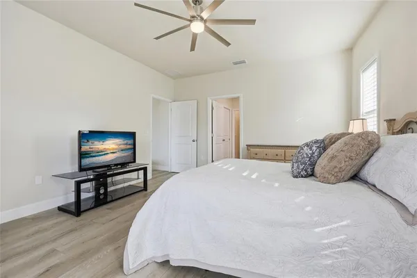 a bedroom with a bed tv and wooden floor