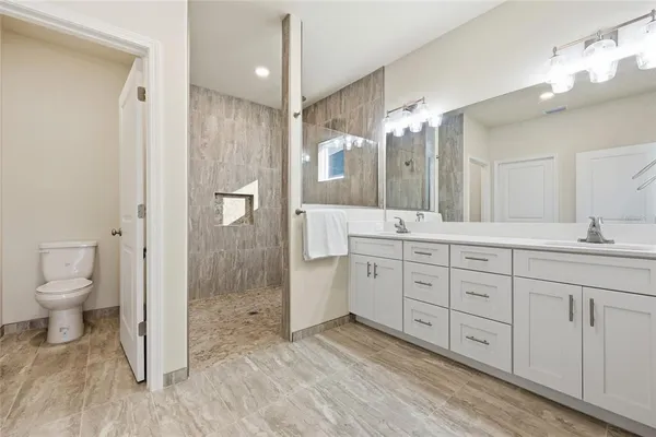 a spacious bathroom with a granite countertop sink a toilet and a shower