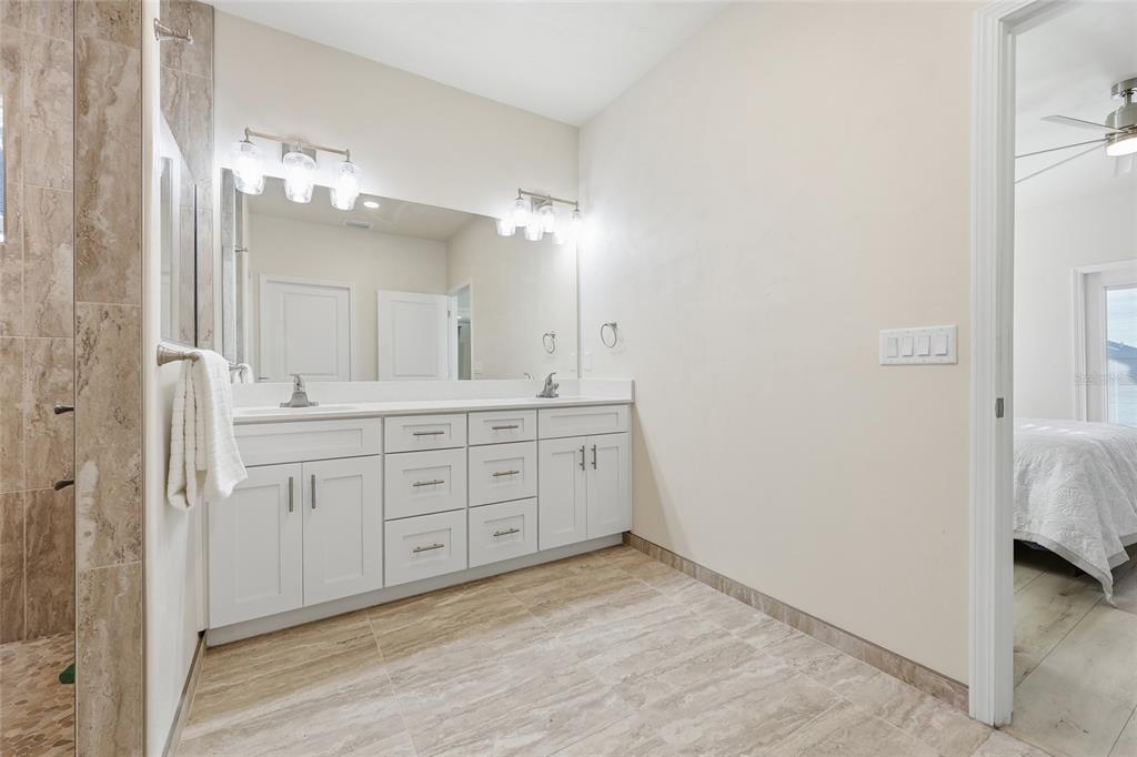 1402 Southwest 67th Drive Gainesville, FL 32607 - Photo 13 of 30 a spacious bathroom with a double vanity sink a mirror and a shower